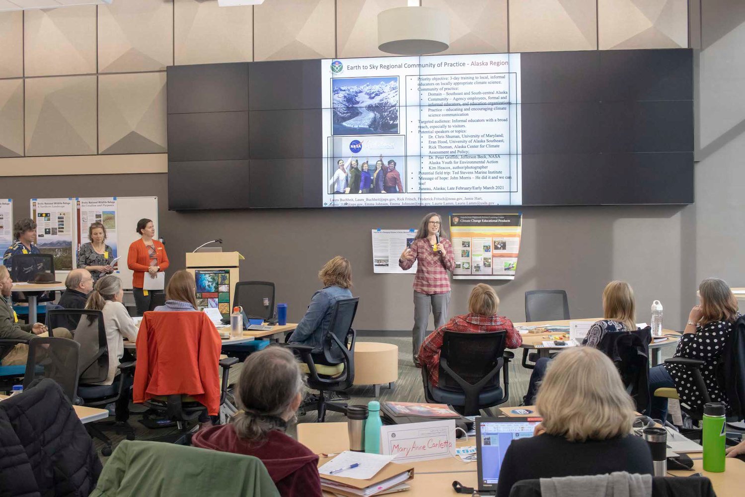 Mary Anne Carletta, back to camera left, and Carol Roig watch the Earth to Sky team from Alaska outline their plans for their region at the October 2019 leadership team training session at Woods Hole, MD. The five-member team from the Upper Delaware was one of the first four regional teams trained.